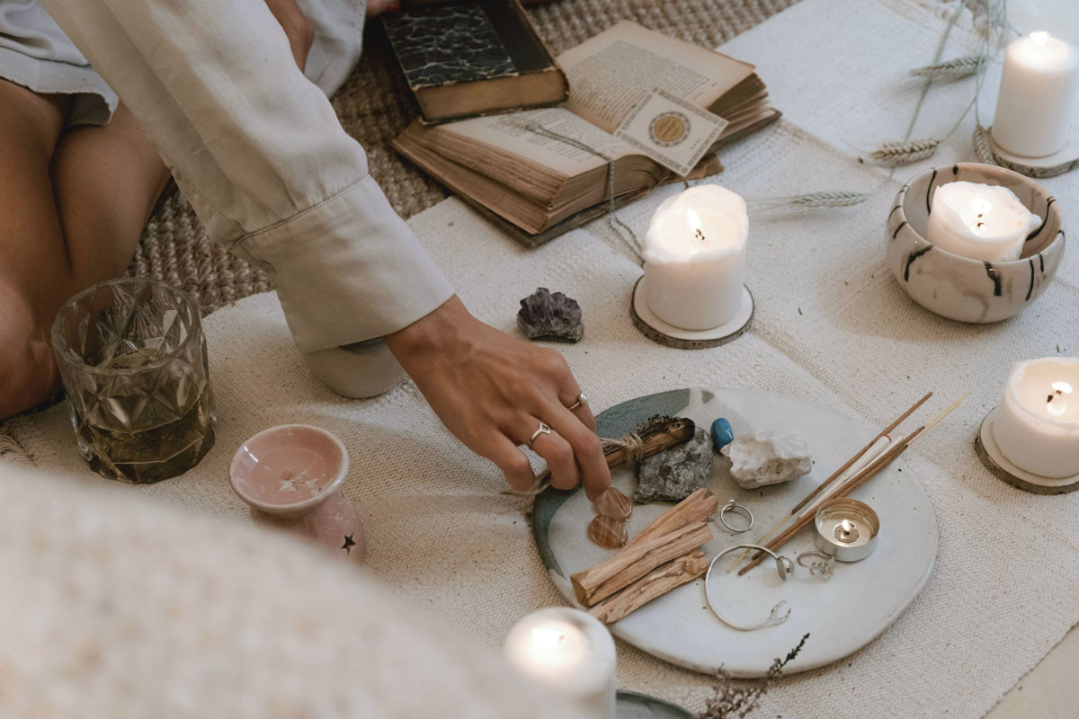 A close-up of a burning ceremony where a handwritten slip of paper is safely lit over a ceramic bowl to release limiting beliefs during a full moon ritual.