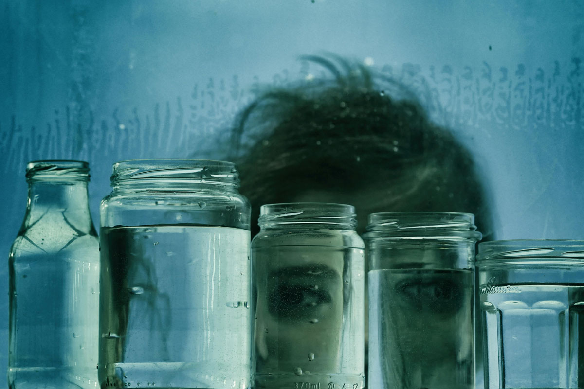 A clear glass mason jars filled with water sitting on a rustic wooden windowsill under the soft light of a full moon.