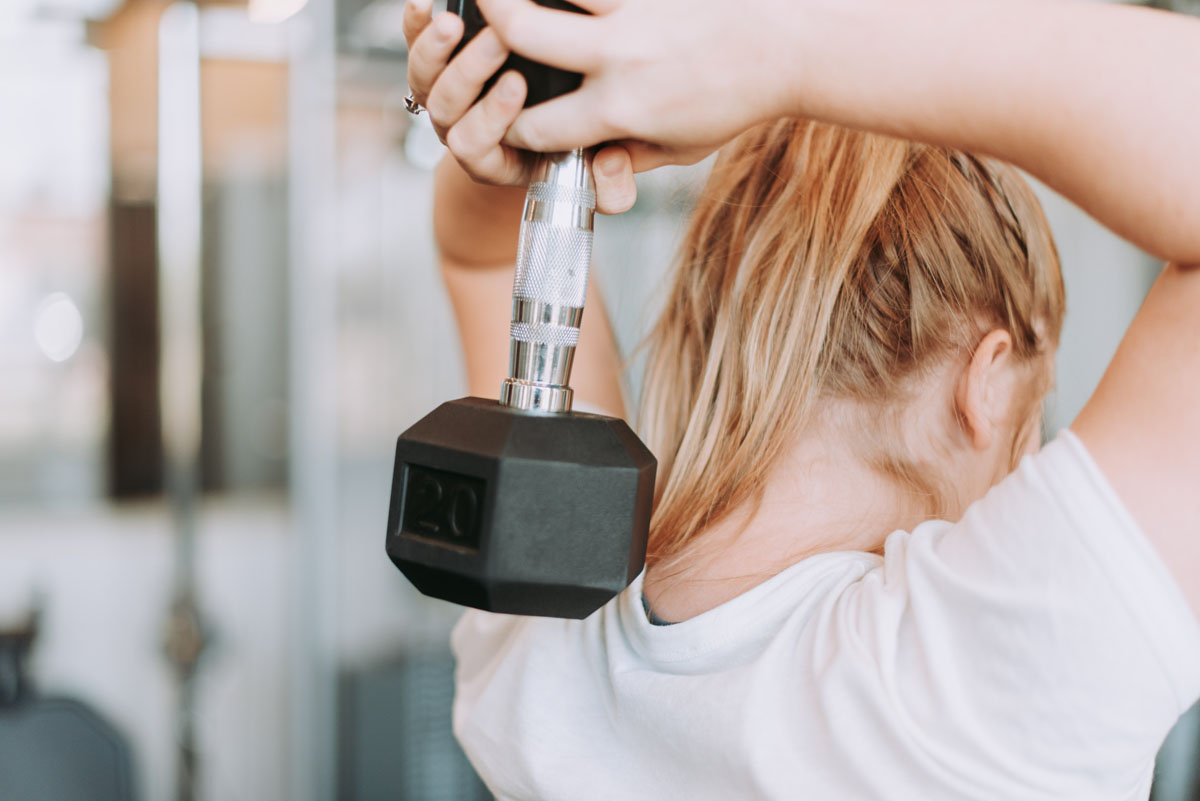 A woman with a ponytail lifts weights.