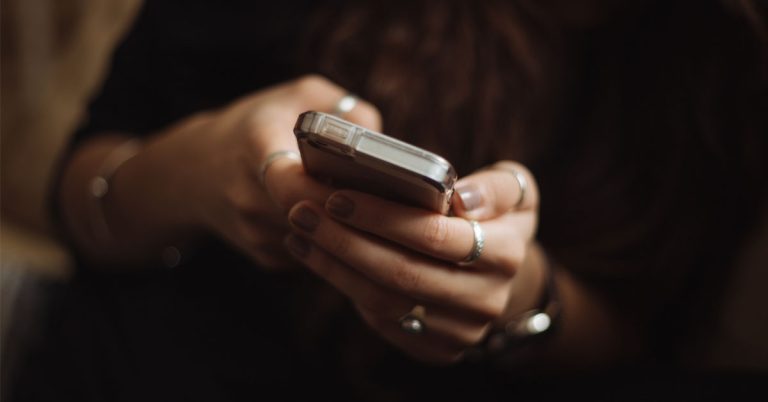 Close up of hands holding smartphone, representing social media screen time and digital detox tips.