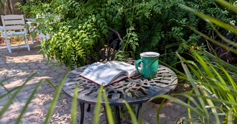 Open paper notebook next to a warm mug of herbal tea on a rustic table, representing journaling tips.