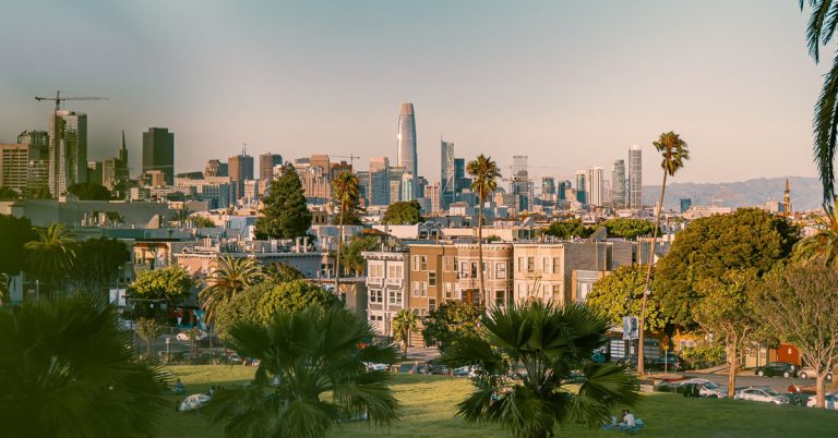 A view of a city skyline from a green park in an example of slow living in the city.