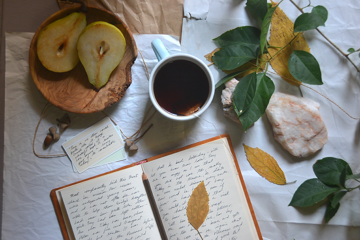 An affirmation journal lays open on a table next to leaves, tea and greenery.