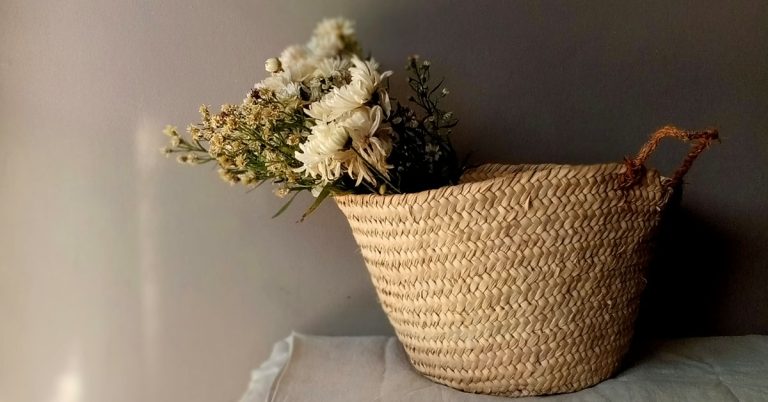 A straw basket sits on a table filled with white flowers.