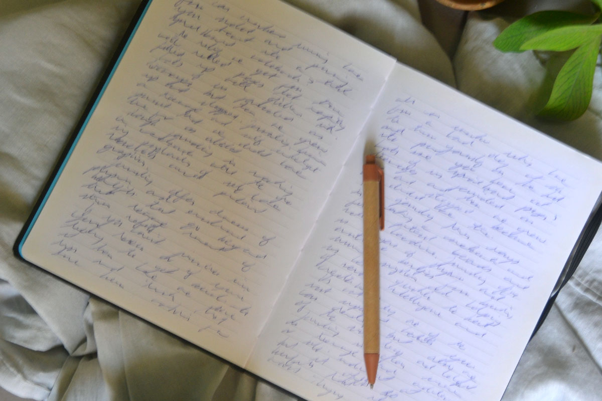 A journal lays open filled with handwriting with a brown pen on top.