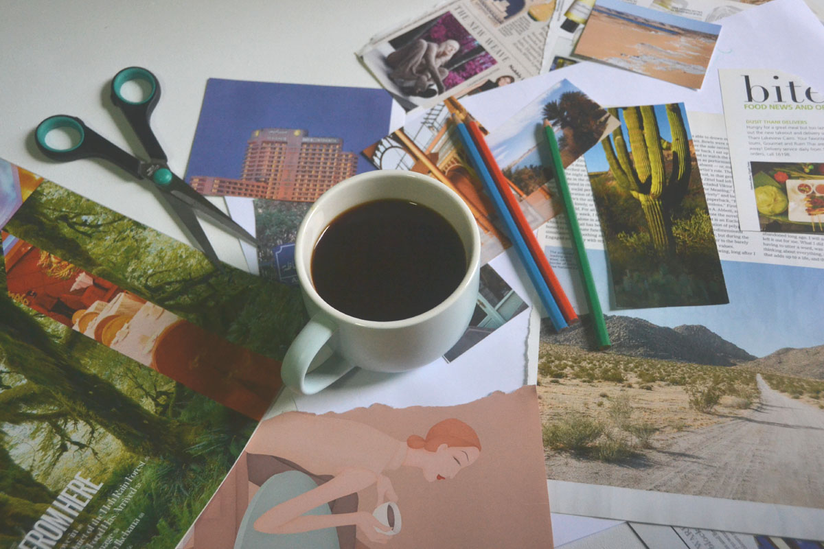 Materials for a vision board lay on a table next to a cup of coffee.