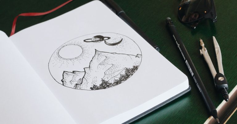 A notebook filled with journaling ideas lays on a black desk.