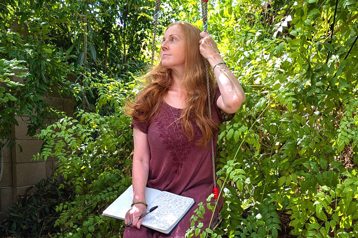 Dee sits in a garden writing in her journal.