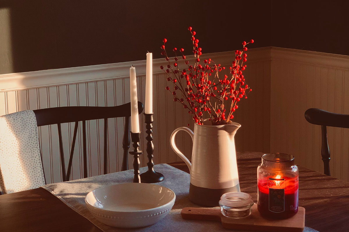 A vase with red and white candles stand on a table.
