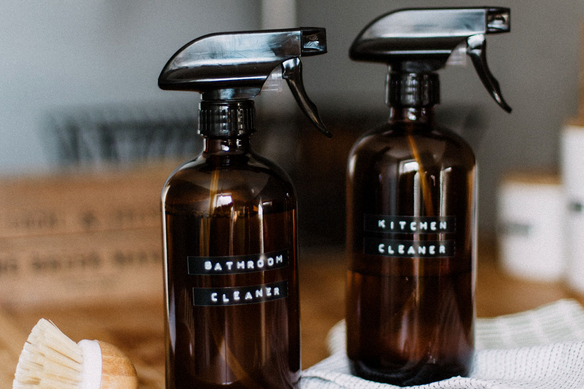 Two bottles of cleaning fluid stand on a wooden table.