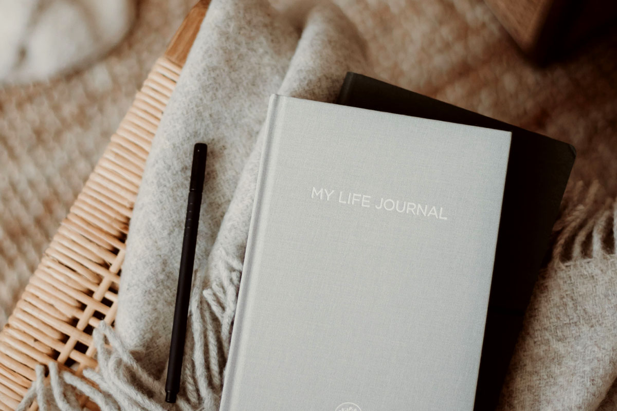 A commonplace book lays on a chair on top of a grey blanket.