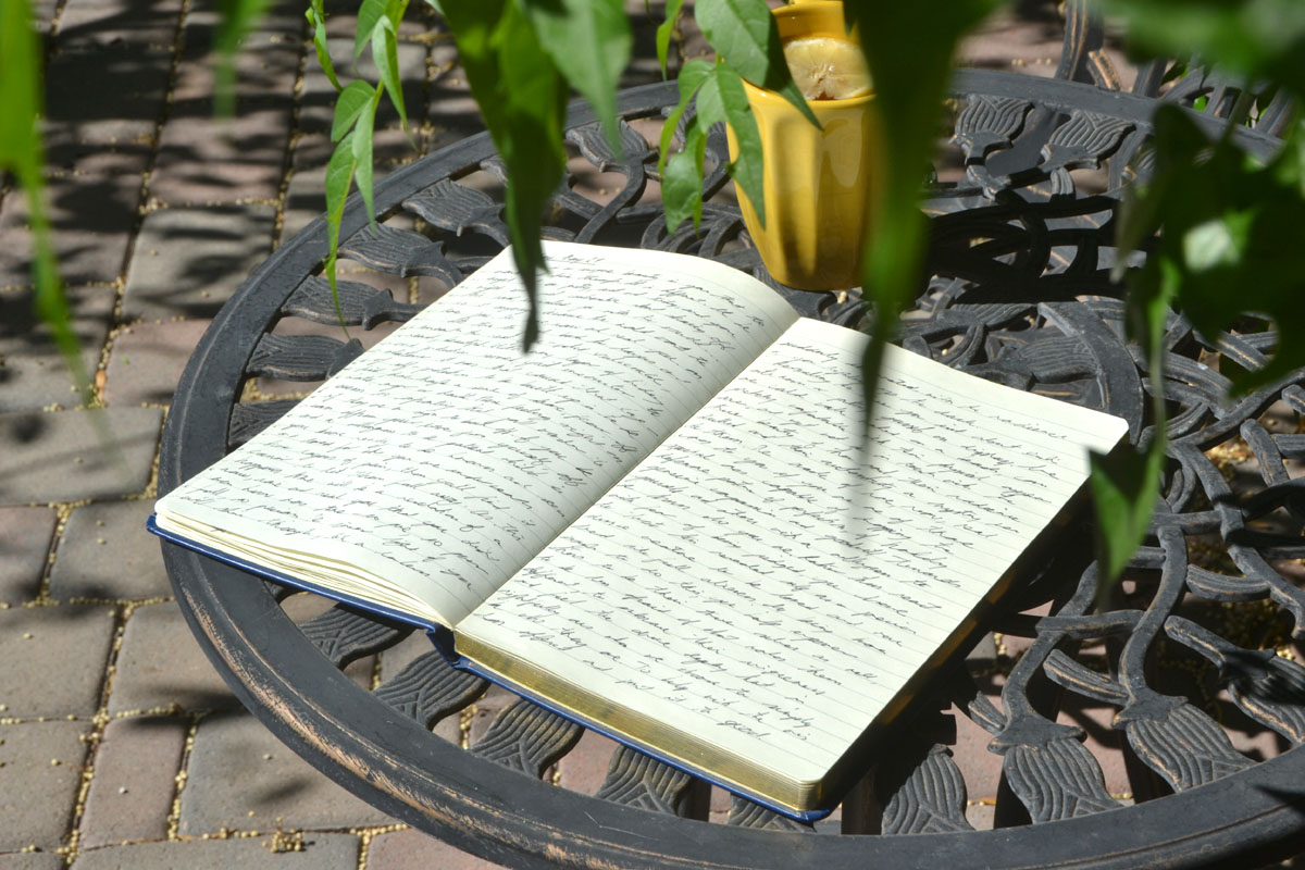 An open notebook lays on a garden table. 