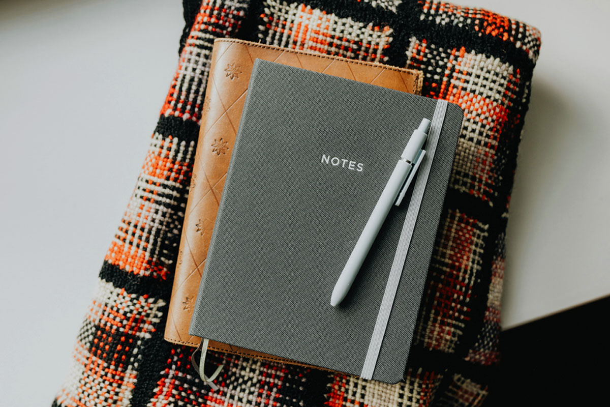 Two journals lay on top of a checkered blanket ready for journaling in December.