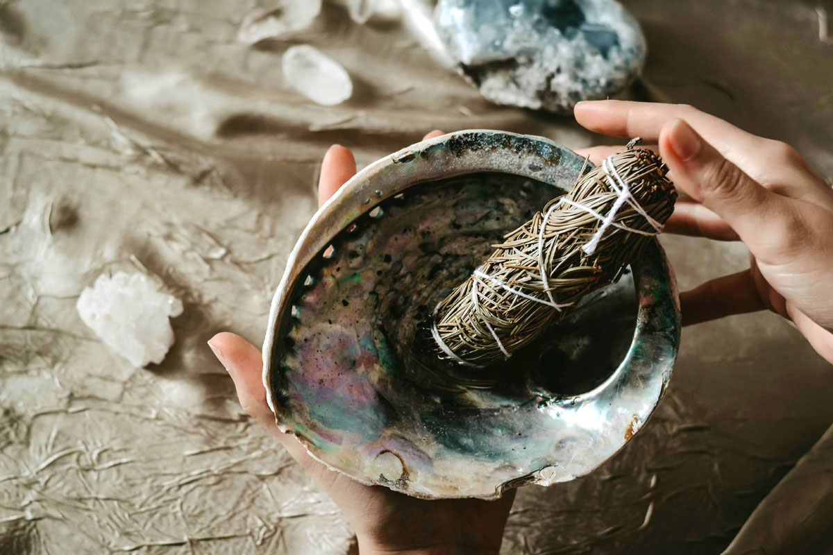 A copper bowl, crystals and smudge stick lay on a table during a spring equinox meditation.