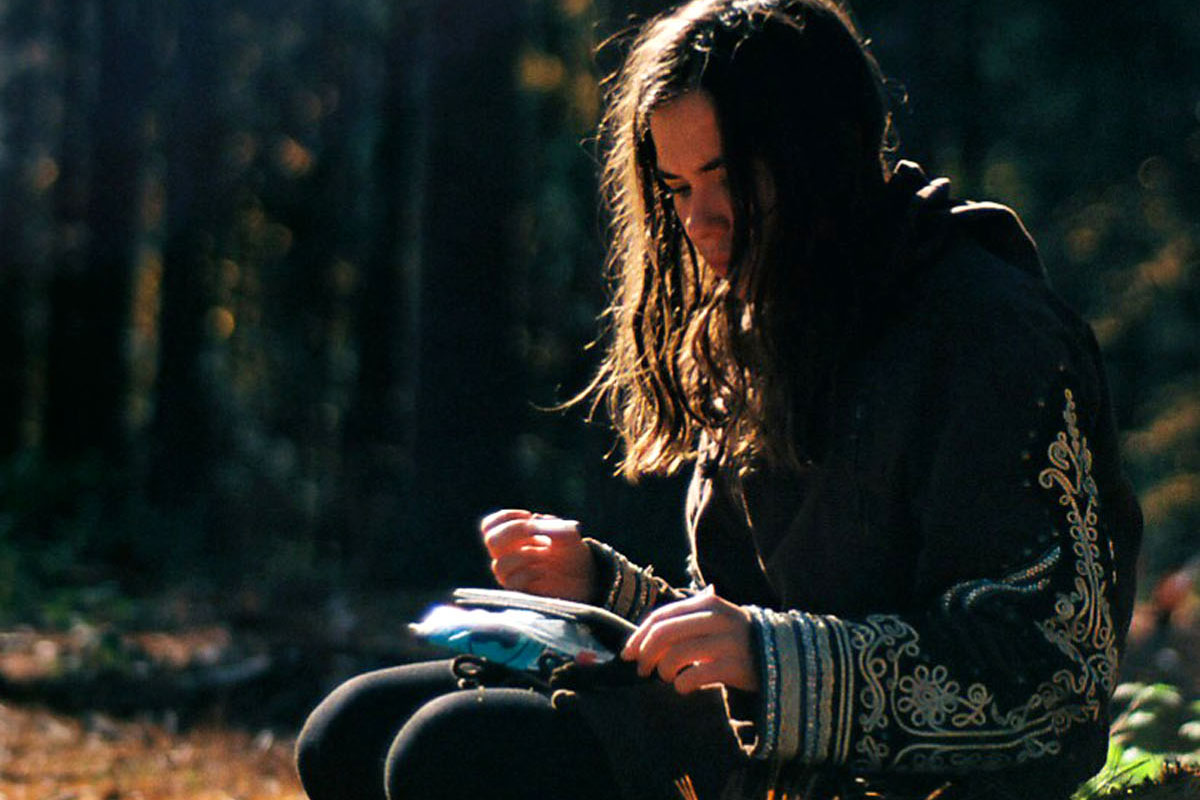 A woman sits in the sun writing in her journal.