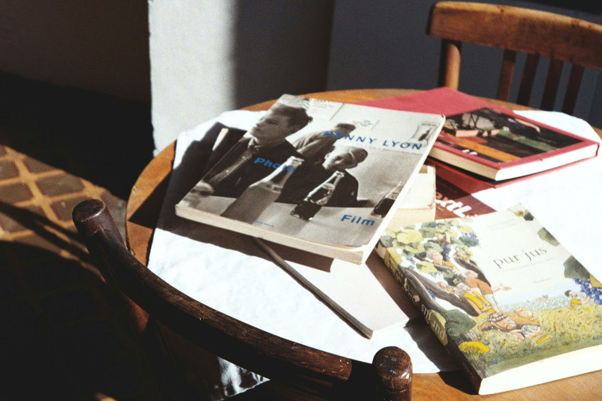 Books and magazines lay in piles on a round wooden table. 
