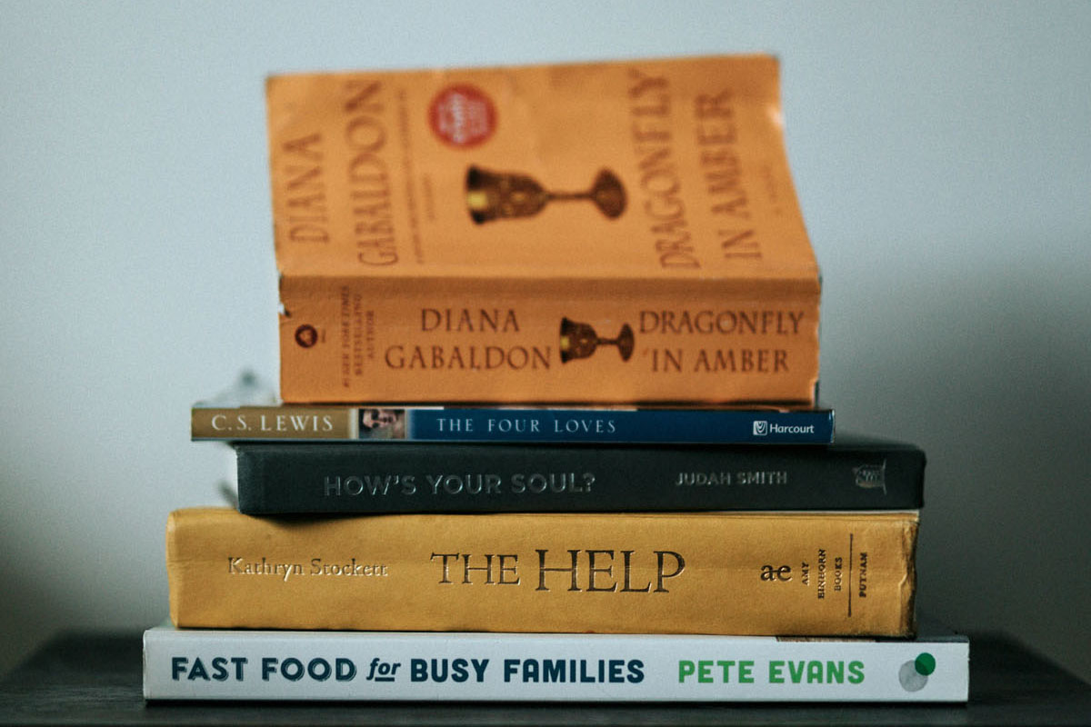 A stack of colorful books and novels lay in a pile on a table. 