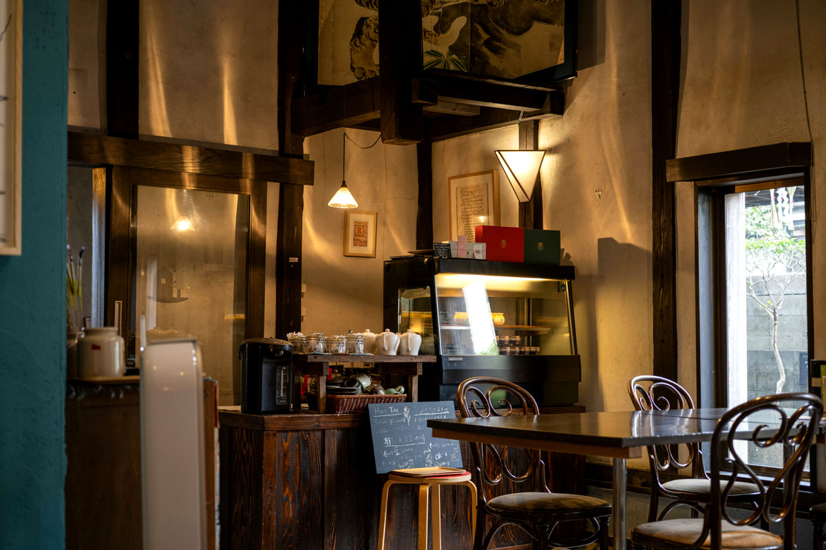 A cafe lined with wooden chairs and baked goods behind a counter. 