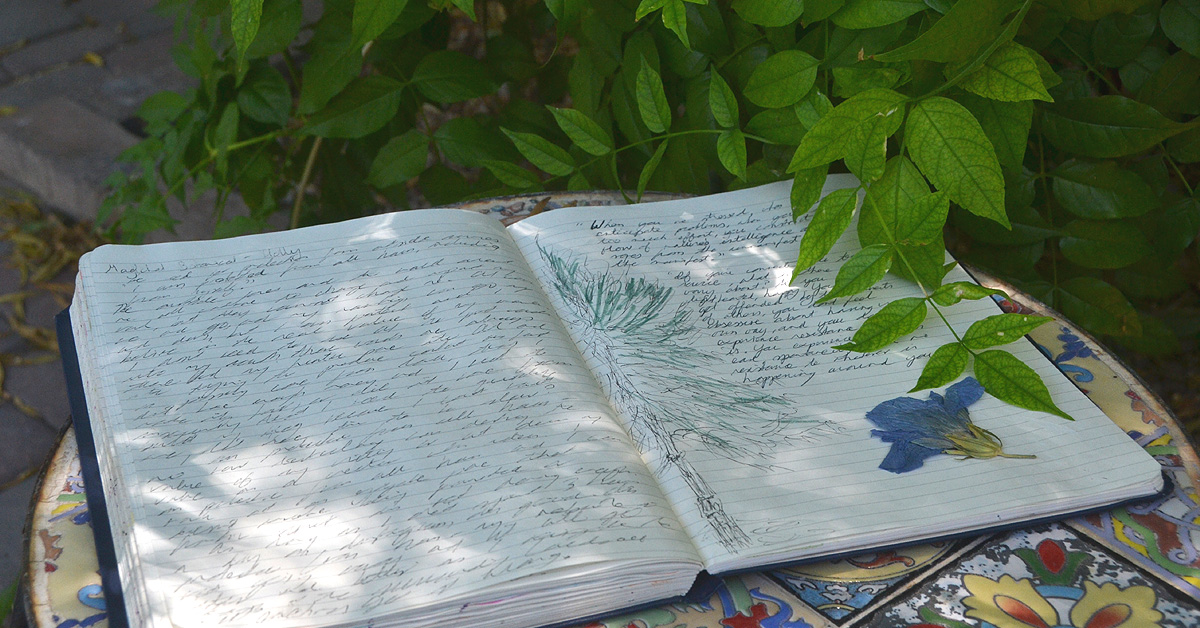 A gratitude journal lays in the sun on a garden table.