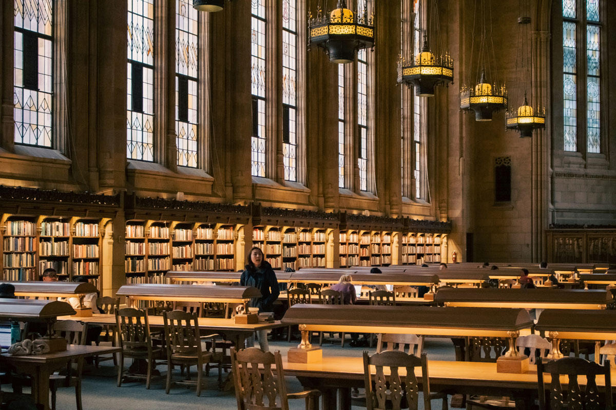 A reading room in an old library full of leather furniture and long wooden tables. 