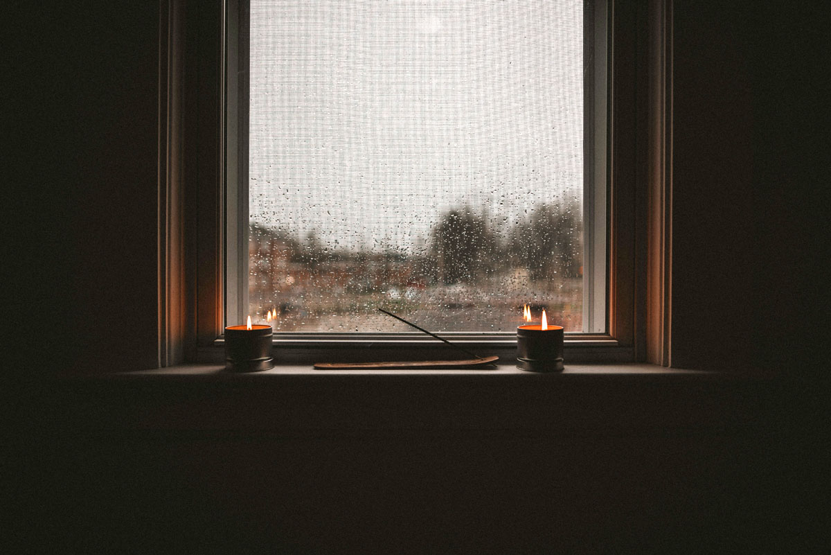 Candles burn on a dark windowsill as it rains during NaNoWriMo.