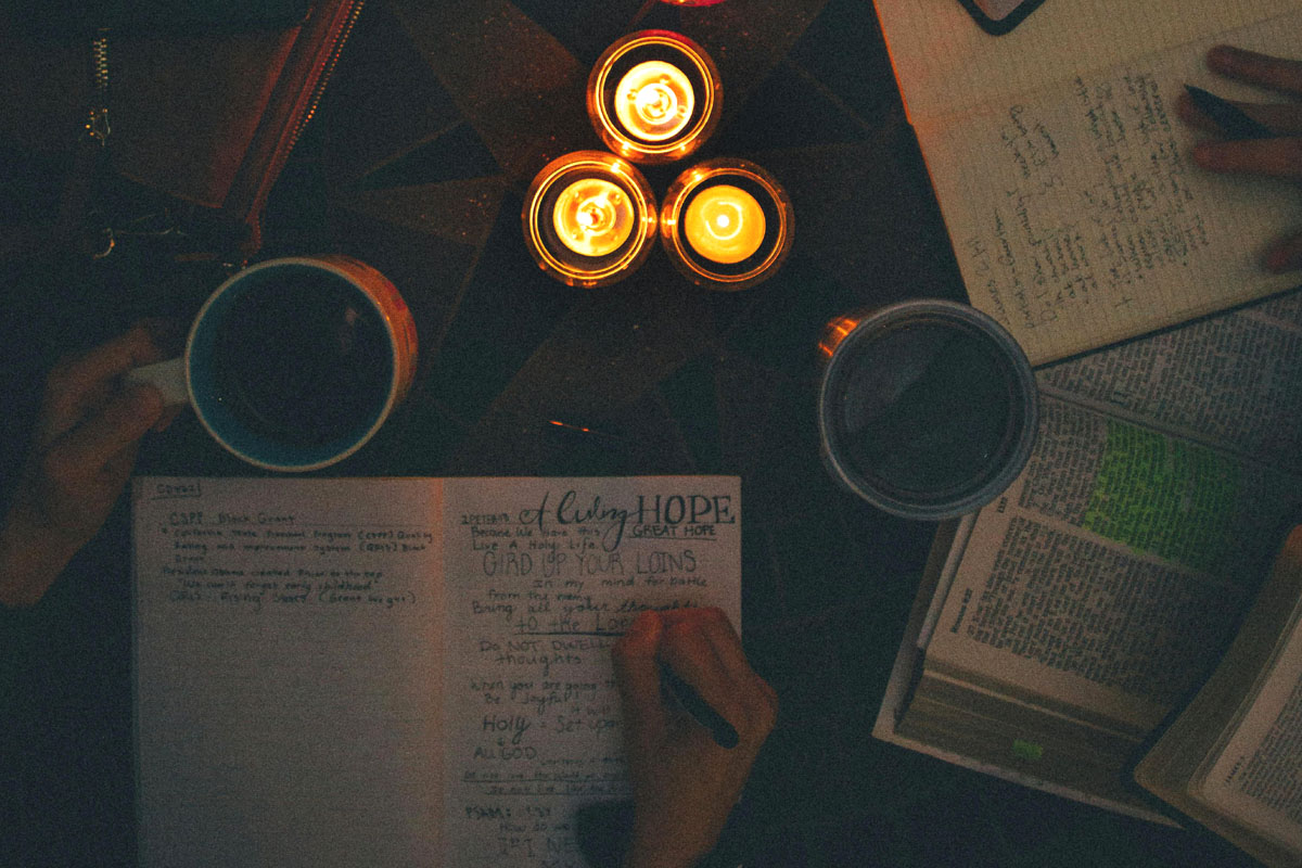 A woman journals on the floor by candlelight.