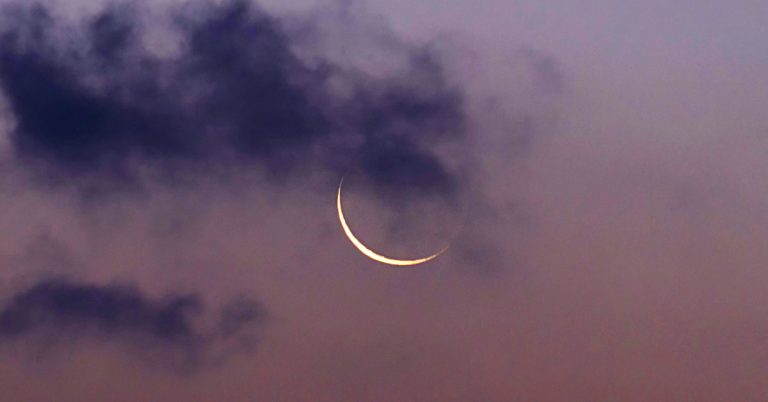 A new moon with a thin crescent shines through the crowds against a rosy sky.