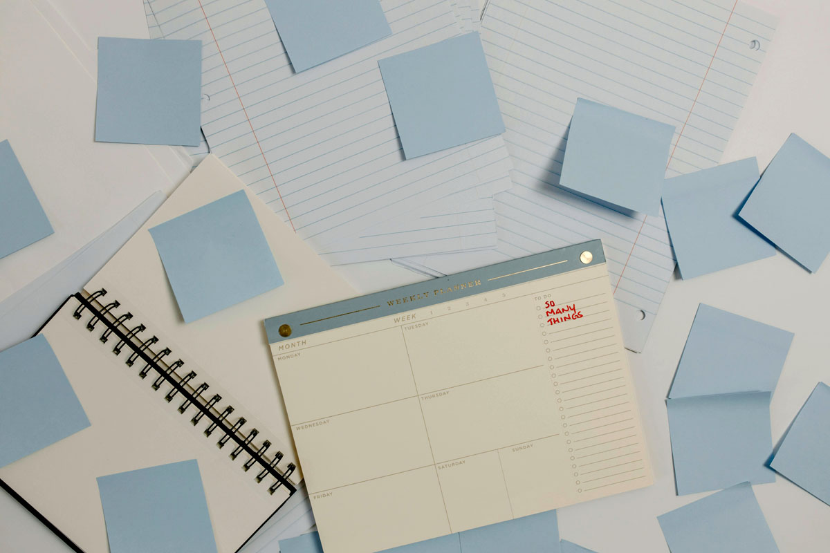 A calendar and piles of postit notes lay on a desk.