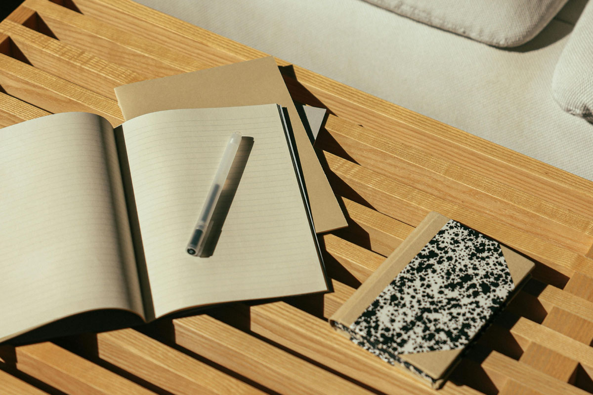 Several journals lay open on a wooden desk in golden light..