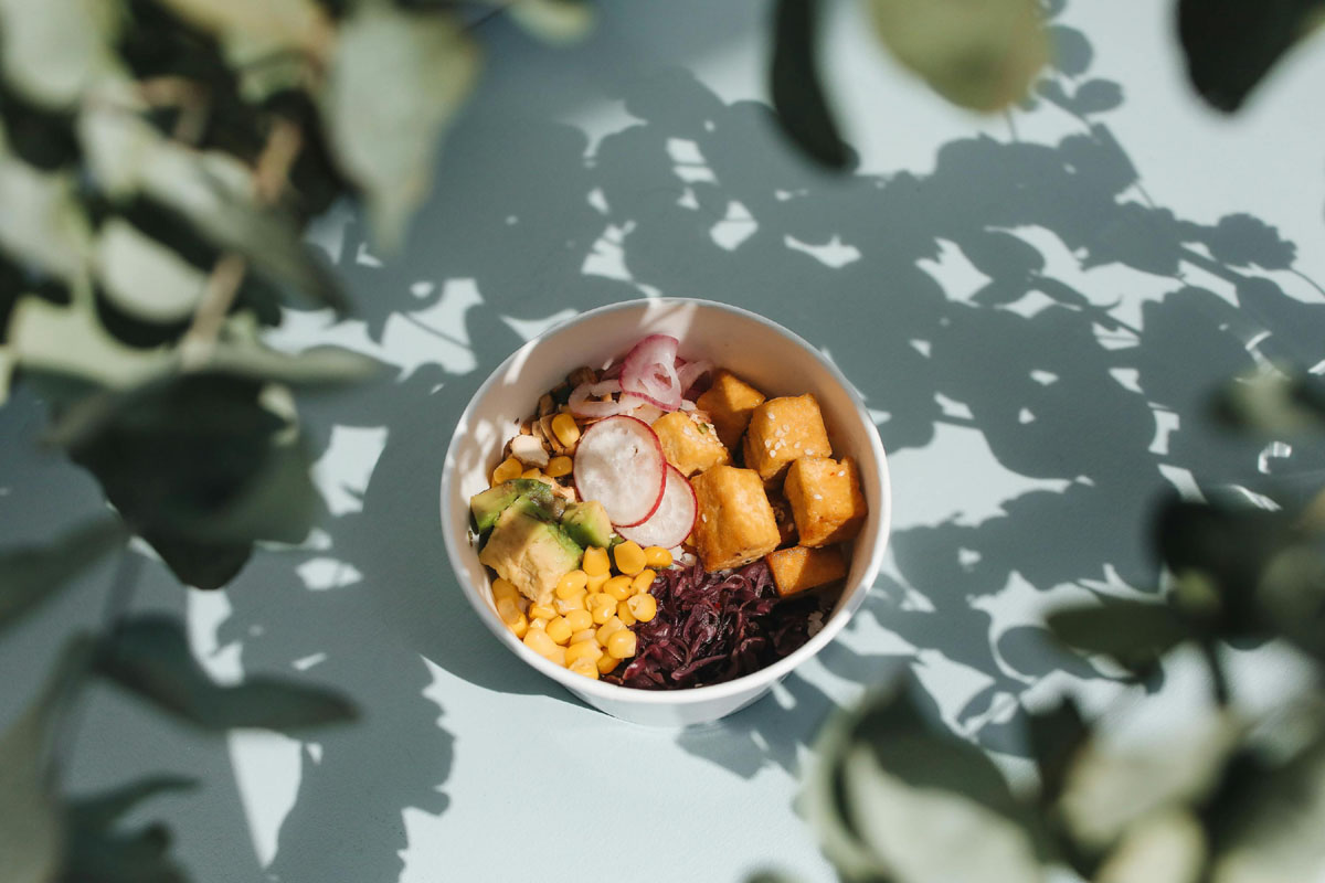 A bowl of colorful salad lays on a sunny table.