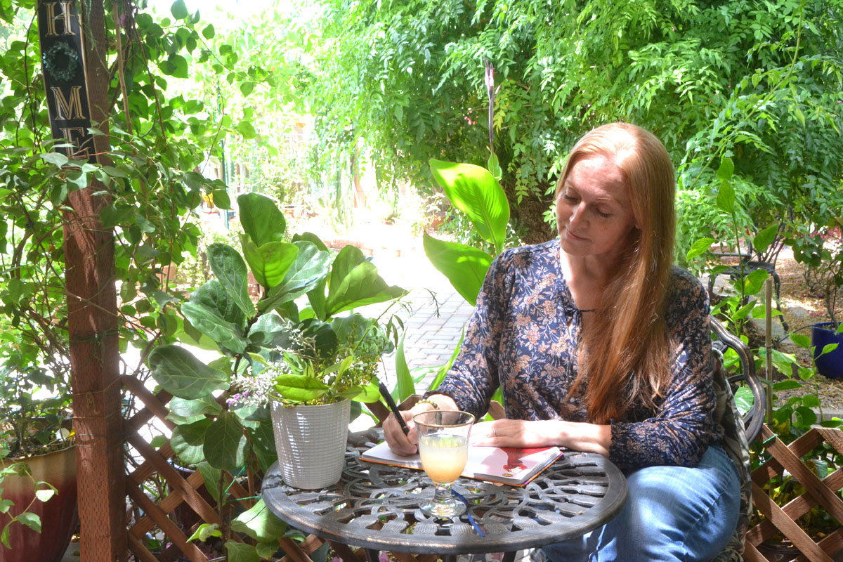 Dee sits in her garden writing in her journal.