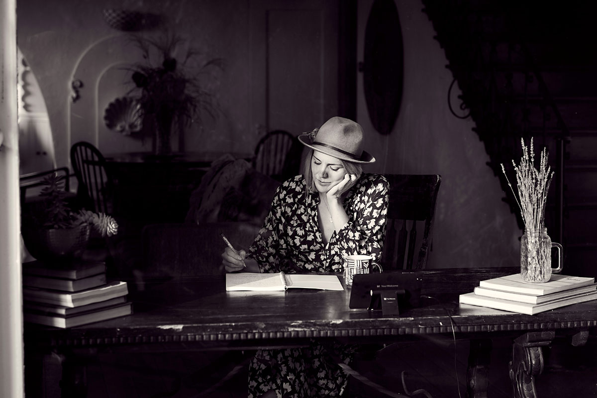 A woman sits at a desk writing in a black and white image.