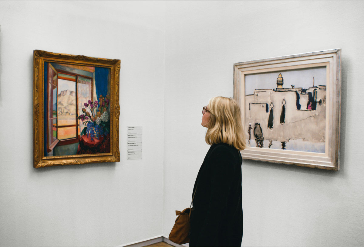 A woman looks at paintings at an art museum.