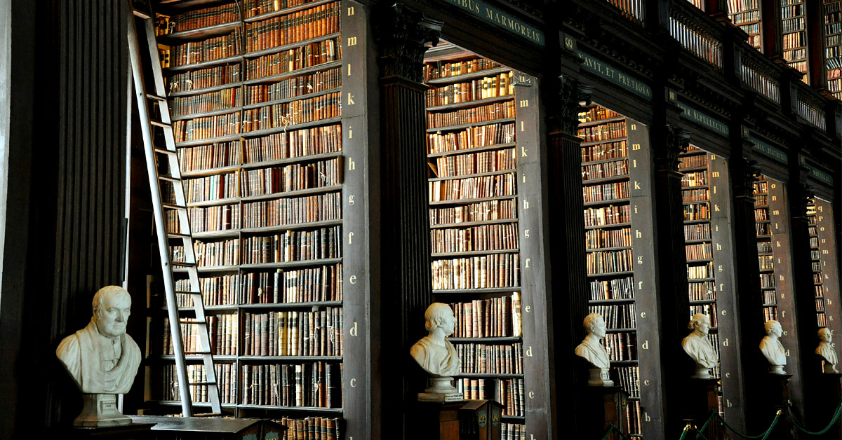 Rows of books at an old library and antique busts.