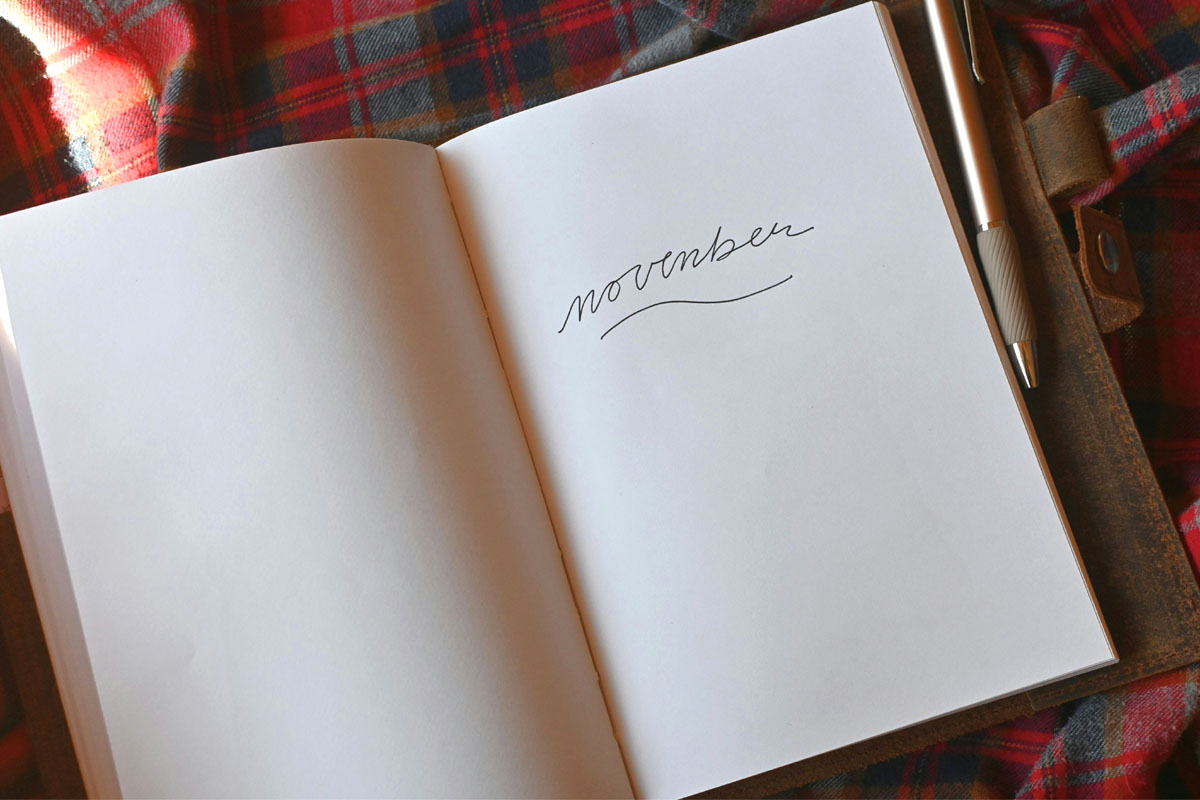 A notebook lays open with the word "november" written on the page in cursive.