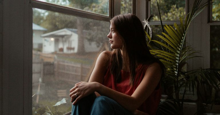 A woman sits and gazes at the view out the window in an example of a phone free morning.