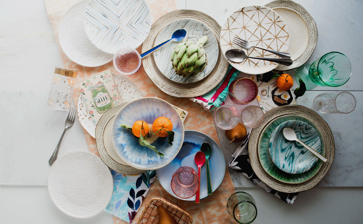 A table is filled with colorful foods and plates. 