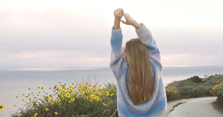A woman does some back stretches during a morning walk as part of a sunday reset checklist routine.