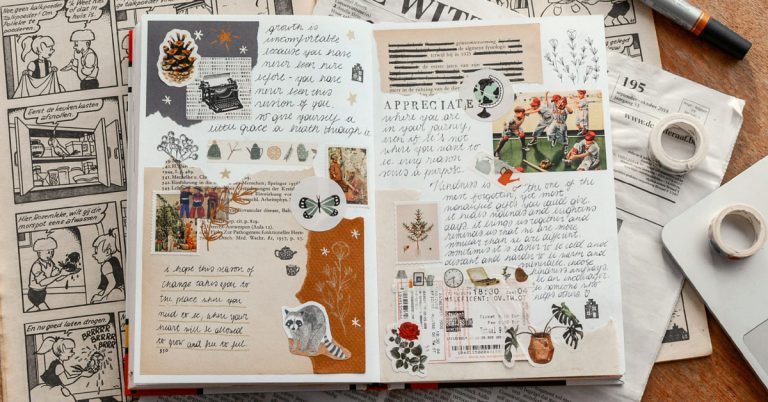 A creative journal lays open on a desk filled with cursive writing, stickers and colored paper.