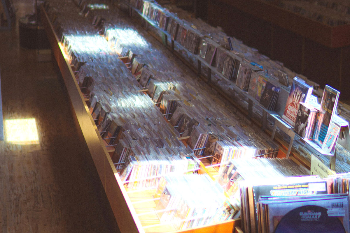A CD shop lit in the sunshine that shows how gen x used to live analog.