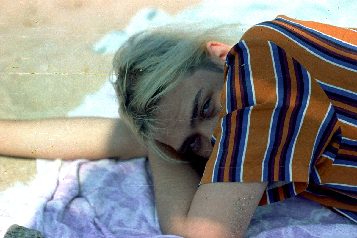 A gen x woman laying on the beach before the smartphone.