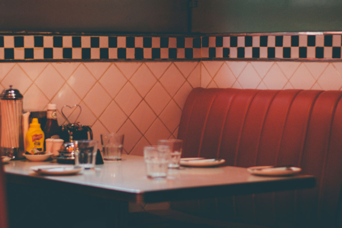 A diner lit in red light with a table full of condiments that was a typical gen x hangout.