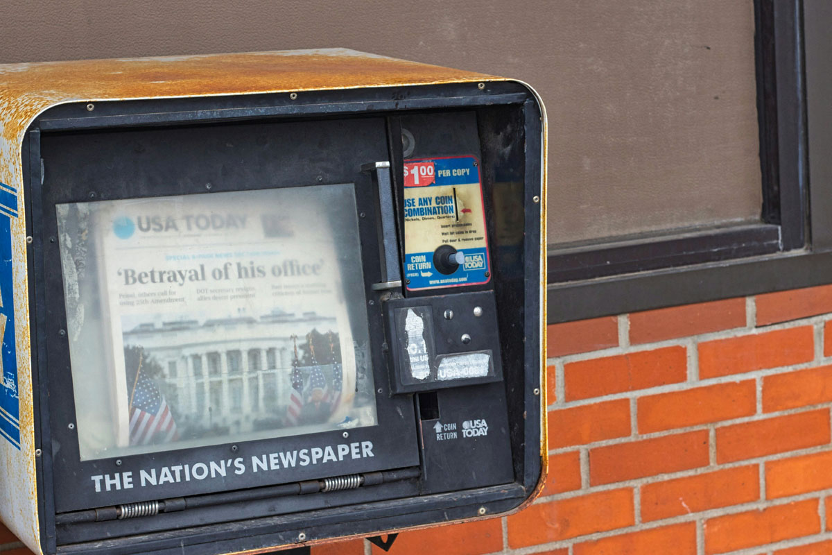 A news stand with copies of the Sunday paper inside.