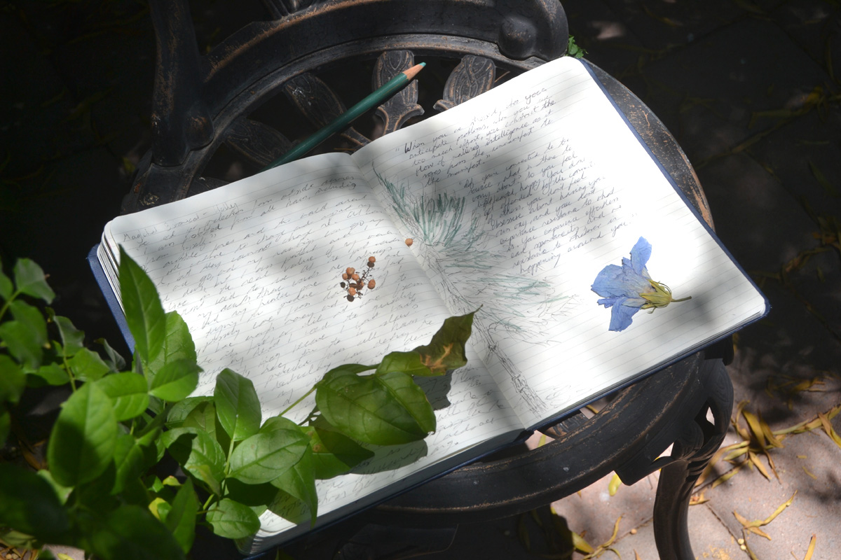 A journal lays open on a garden table.