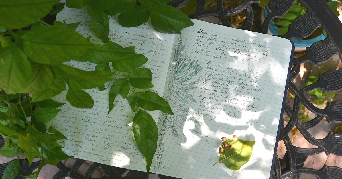 A shadow work journal lays open on a table in a garden.